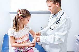 Male doctor examining girls' elbow