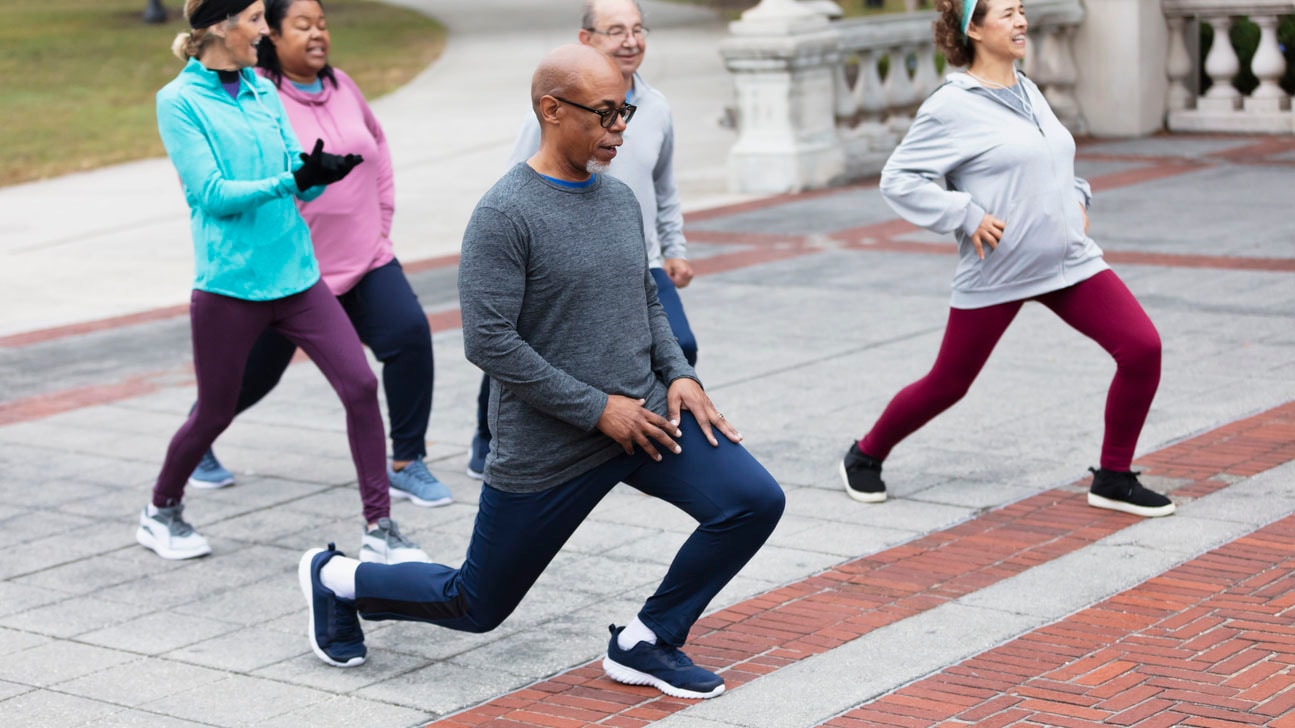 Diverse group of middle-age and older adults stretching in the park