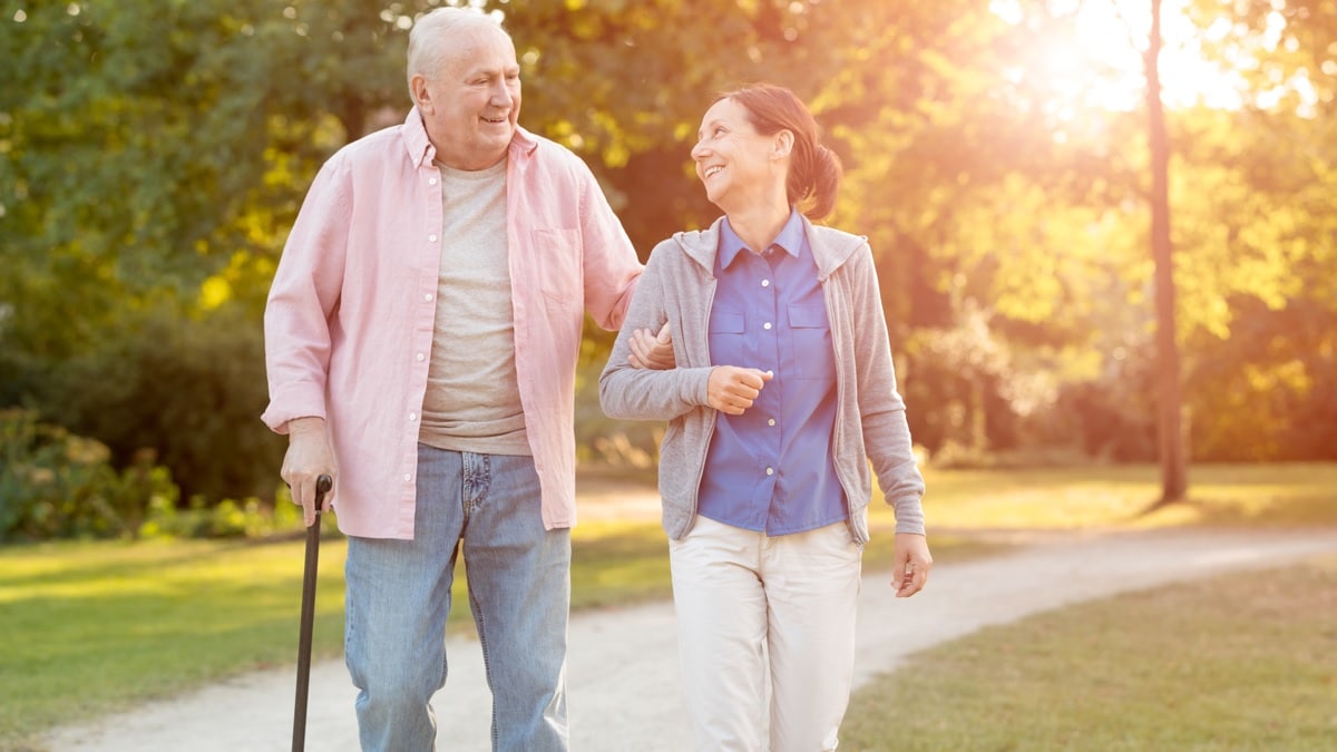 an elderly man and woman walking outdoors