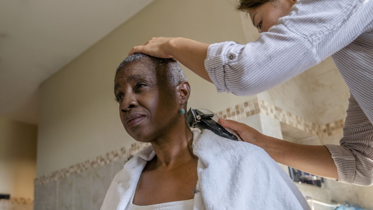 a cancer survivor experiencing hair loss getting her hair shaved off