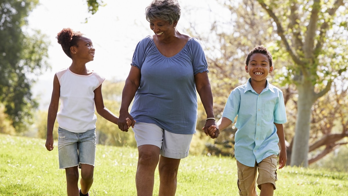 Photo of a grandmother and her two grandchildren walking outside