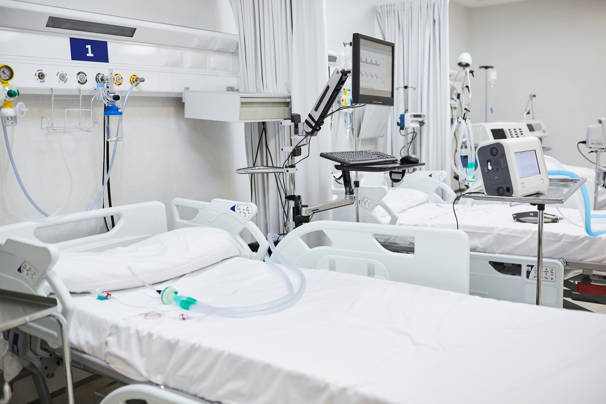 Hospital room with multiple patient beds and medical equipment.