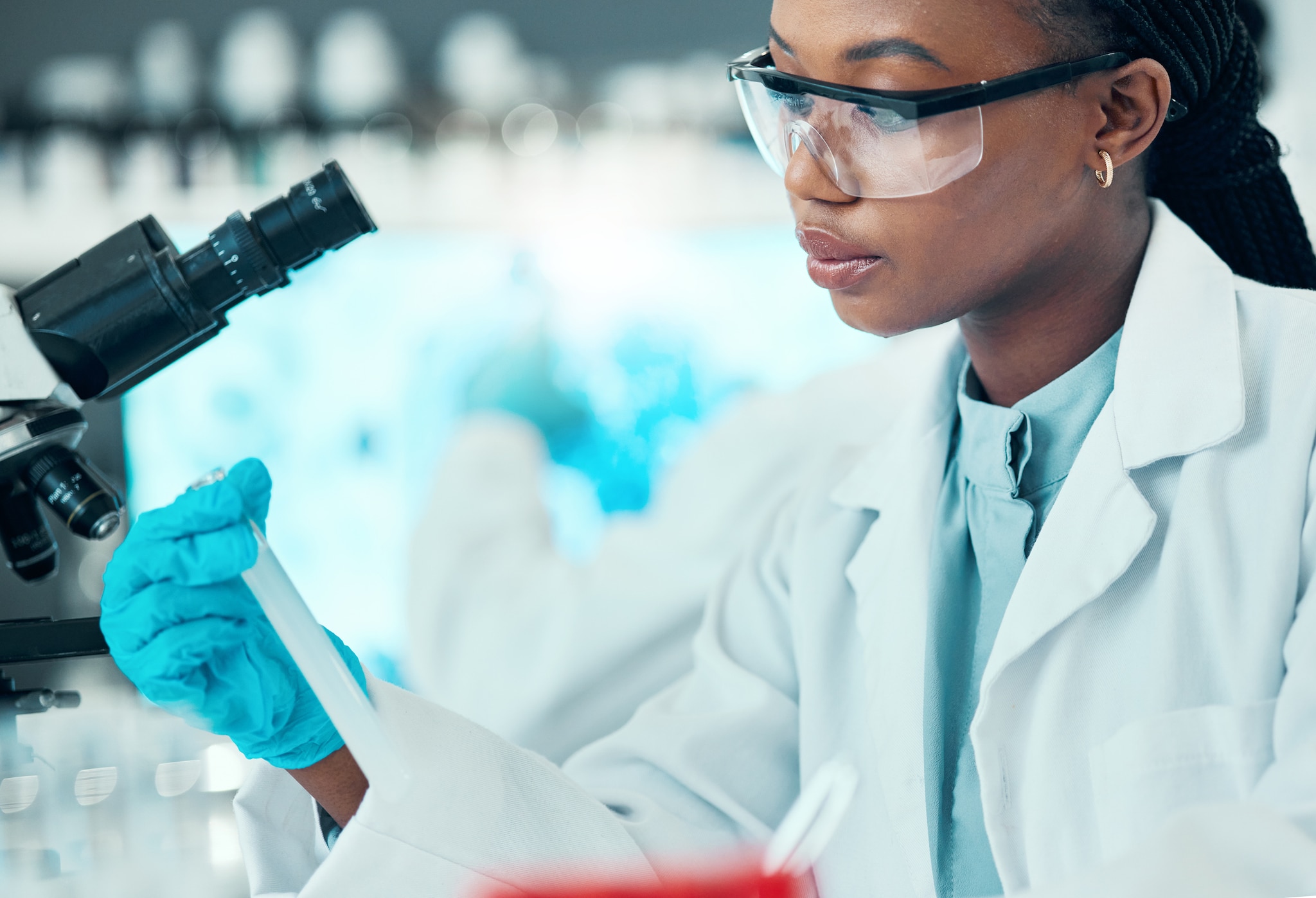 Laboratory worker with a microscope and sample.