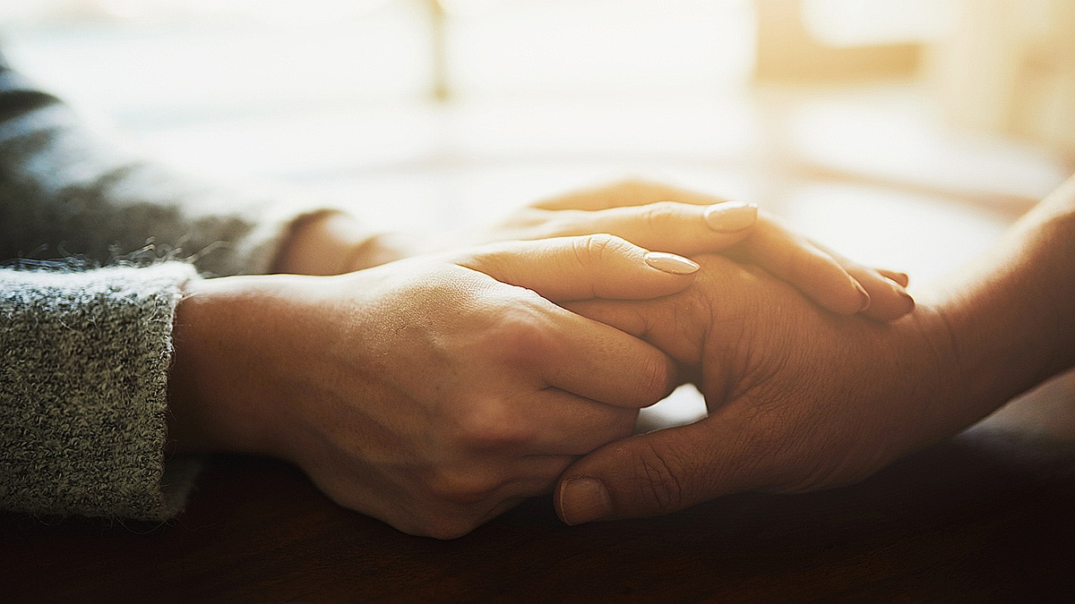 Two female hands holding another hand in a show of caring and support.