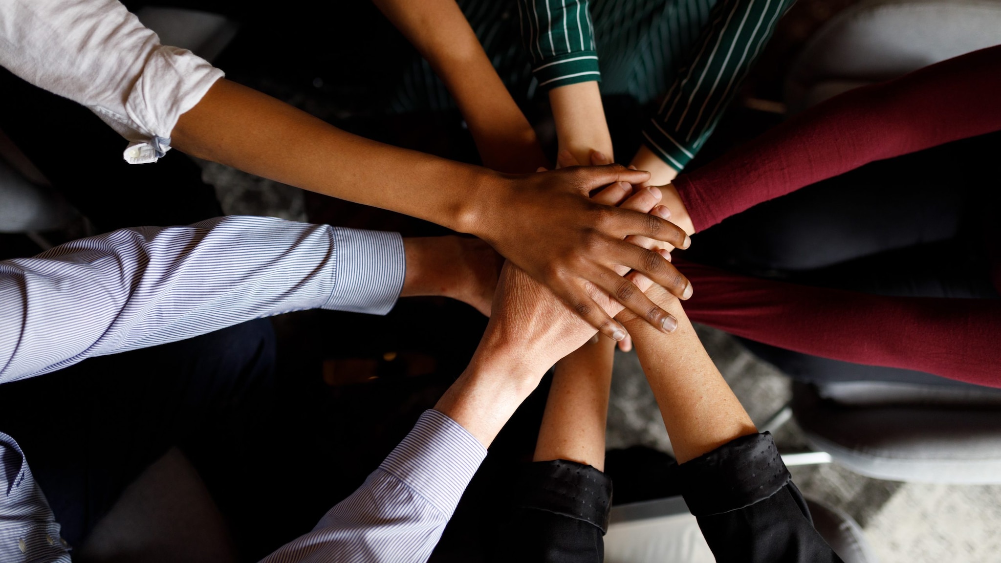 Diverse group of hands clasped together in a group.