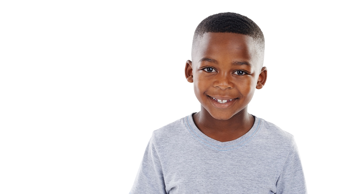 A preschool-age boy standing and smiling