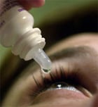 Person putting eyedrops in eye.