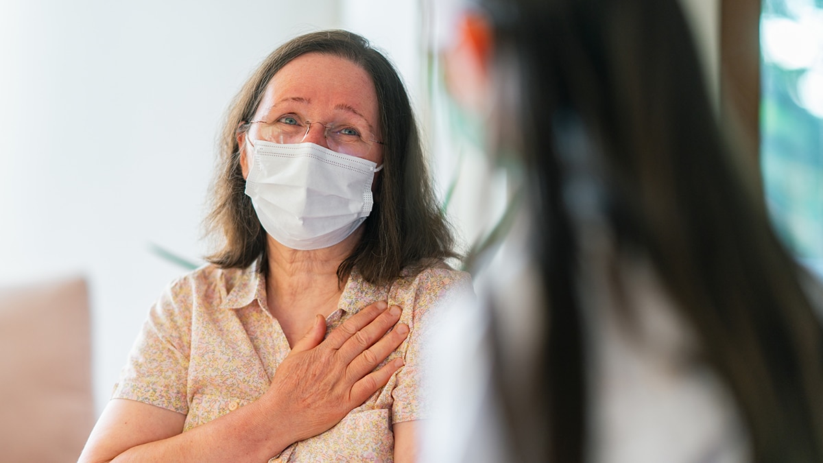 Female doctor with mask talking with her patient.