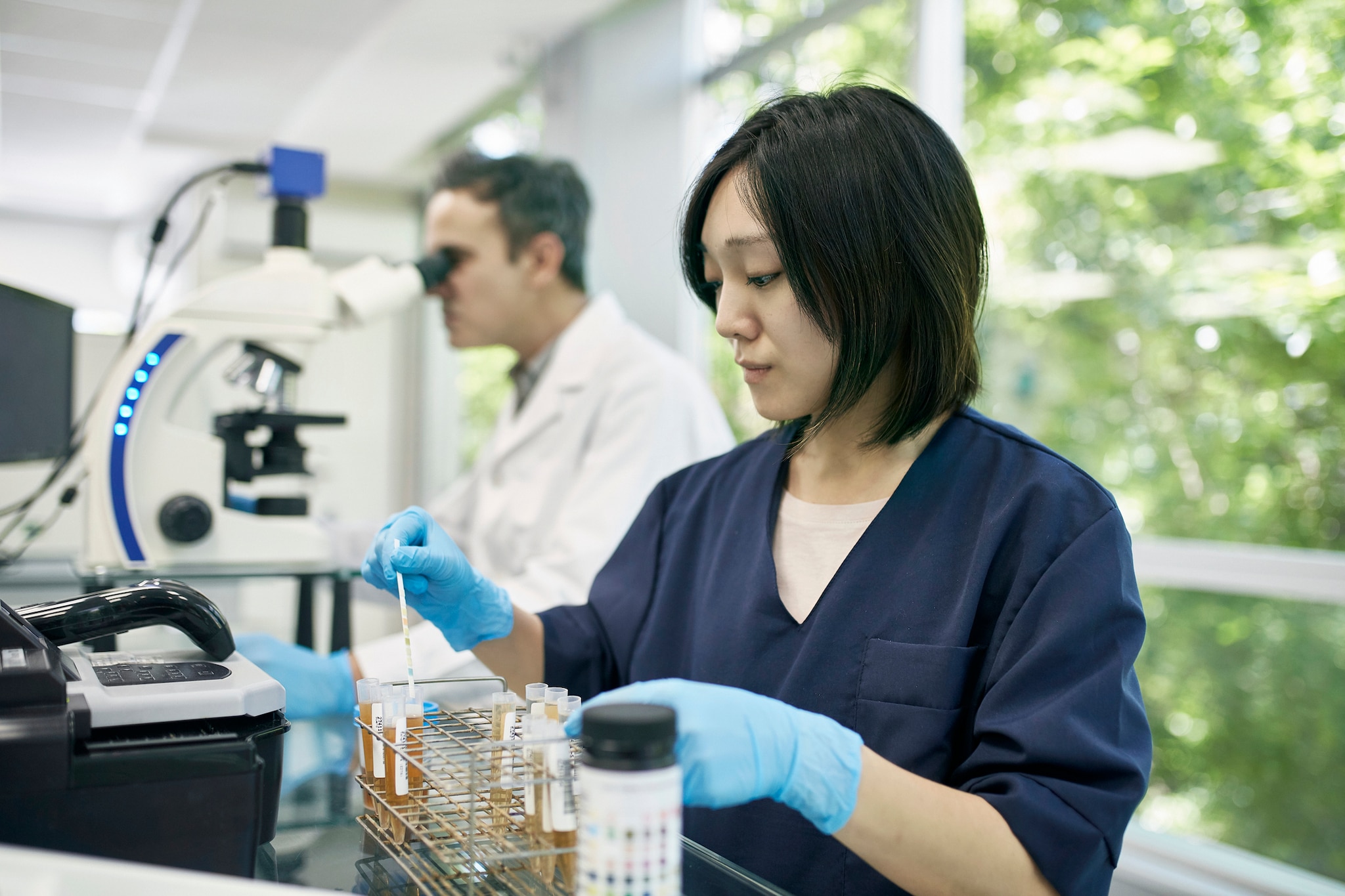 A laboratory worker performing analysis on samples in test tubes.