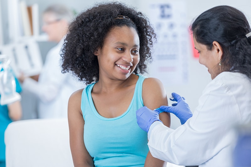 Proveedor de atención médica aplicando una curita al brazo de un paciente pediátrico.