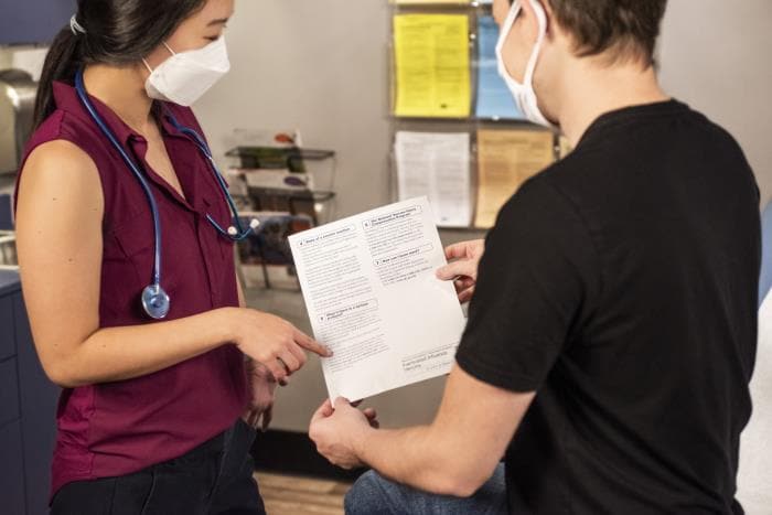 Proveedor de atención médica revisa el material educativo con un paciente en una sala de examen.