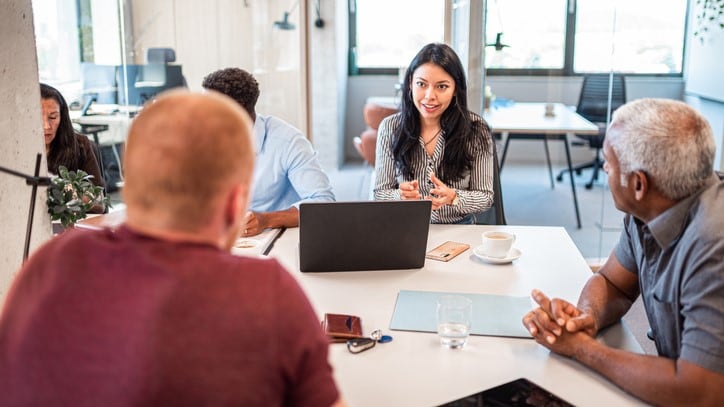 Group of people sitting around a table having a discussion.