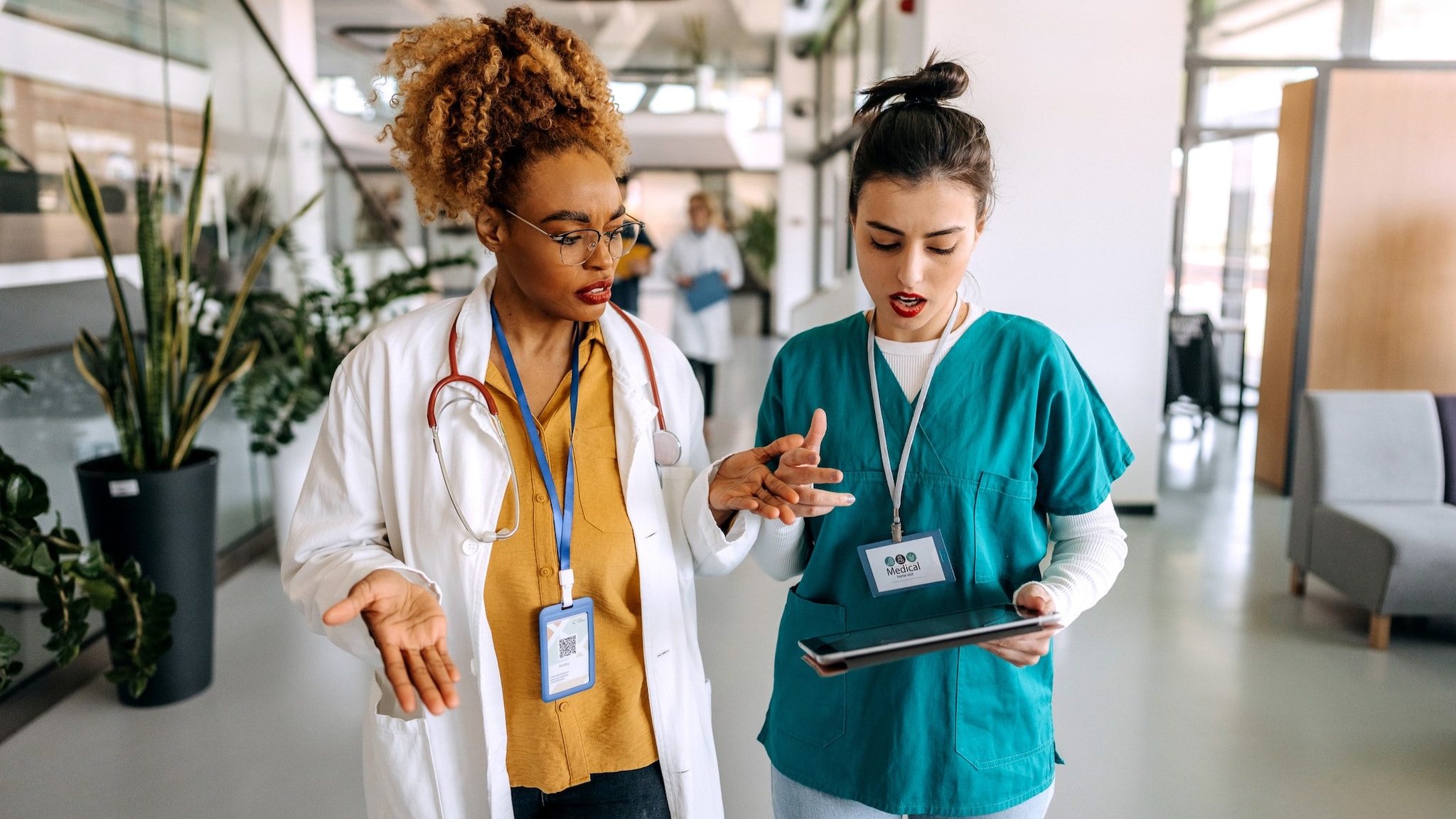 Two clinicians discussing something on their tablet.