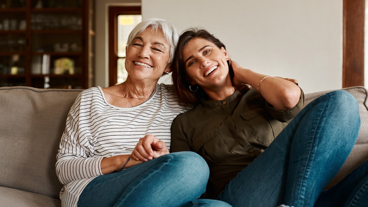 Adult mother and daughter sitting closely on couch