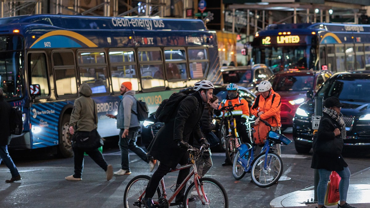 Busy city street with bicyclists, cars, buses, and pedestrians at night