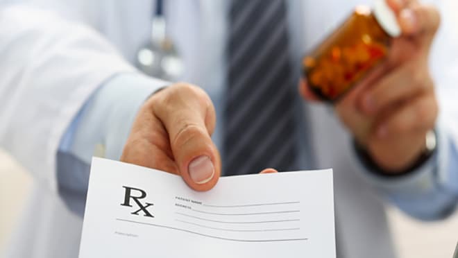 Person holding prescription bottle with a paper that says "RX"