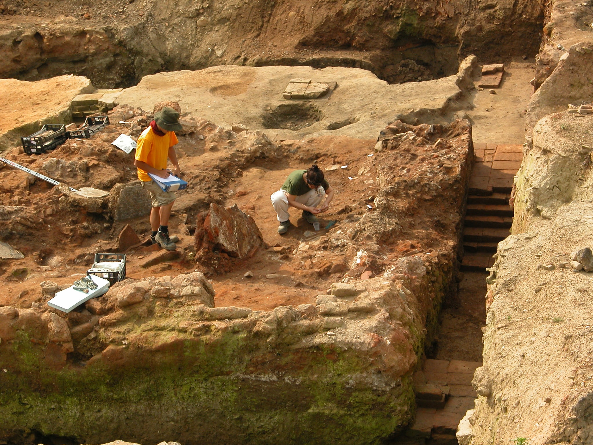 Image of a yellow-colored rocky terrain with two men digging within it.