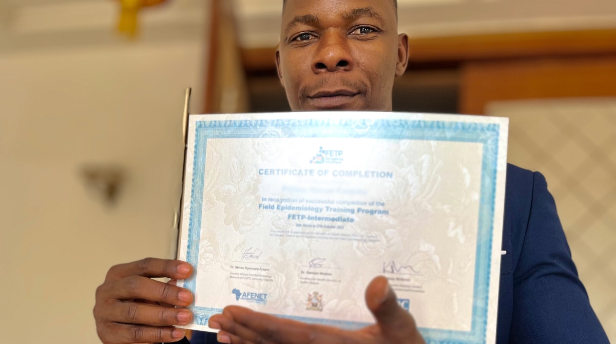 Man holds a training certificate from the Field Epidemiology Training program.