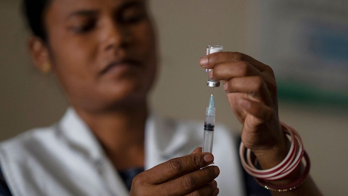 A health worker loads a syringe with vaccine