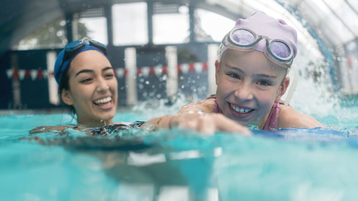 Two girls swimming together in the water.