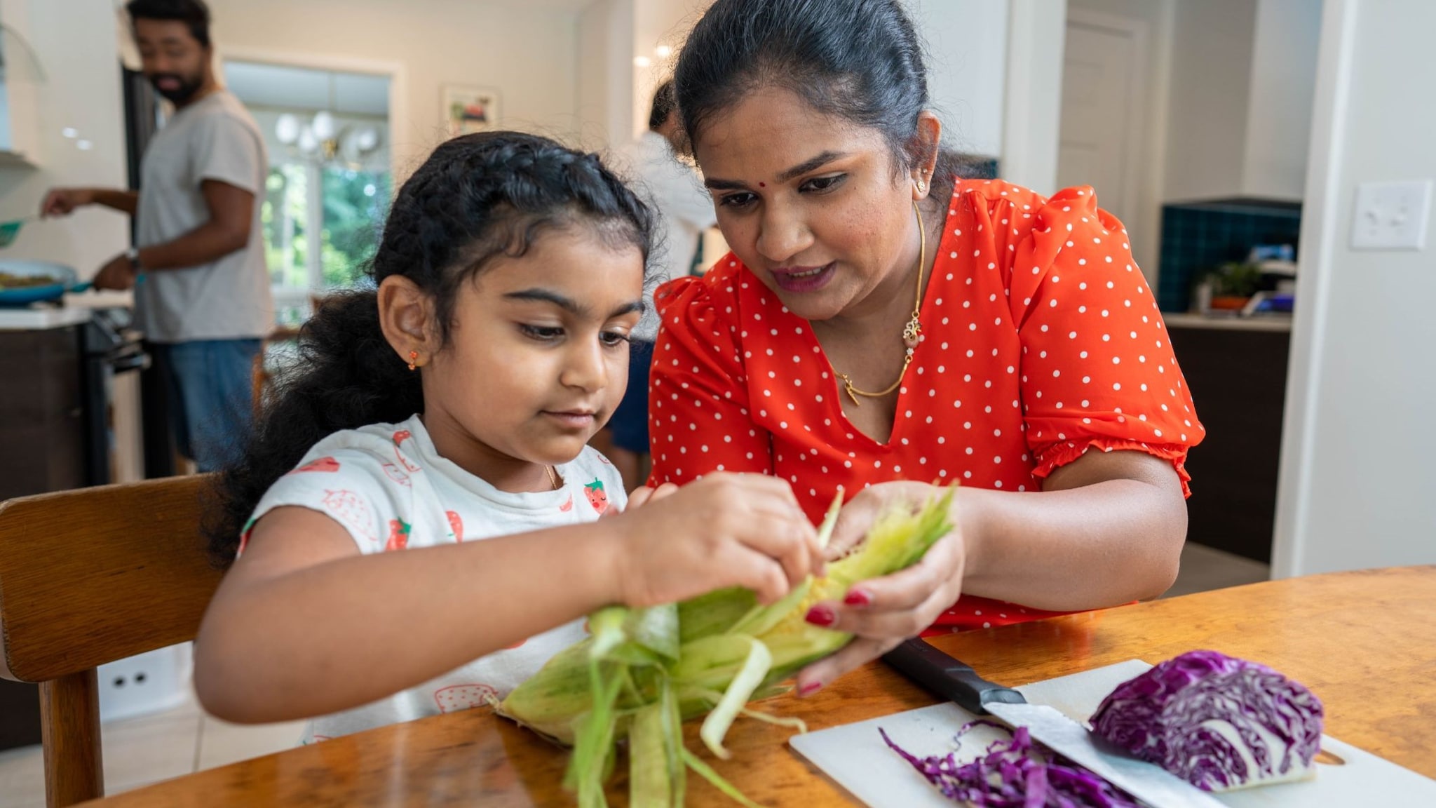 Mother and daughter preparing vegetables at the kitchen table.