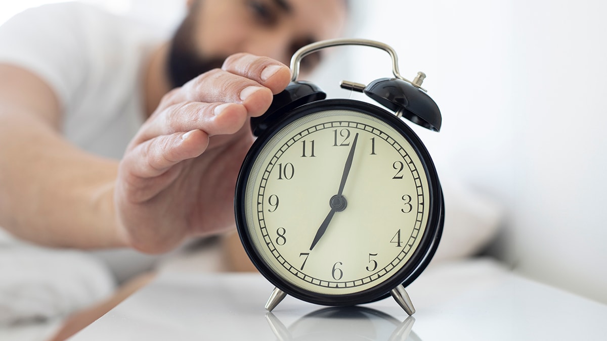 Man reaching over to alarm clock