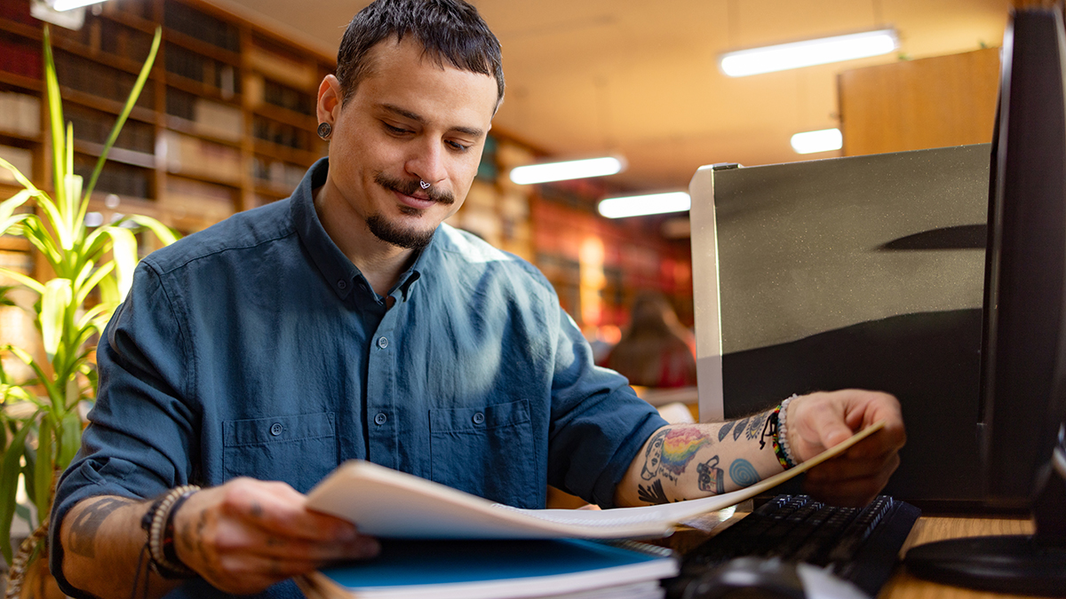 A man sitting at a desk and reading a pamphlet