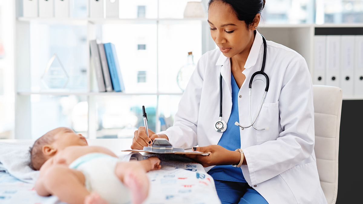 A doctor examining a newborn baby and making notes on her clipboard