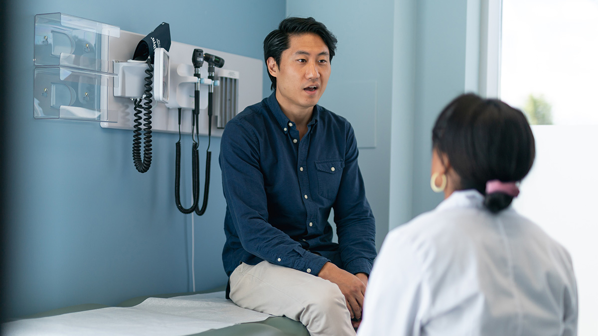 A man sitting in a doctor's office speaking with a medical professional