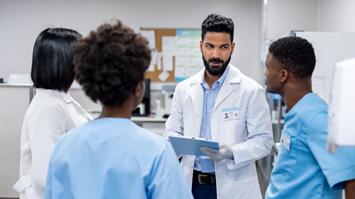 A group of four medical professionals speaking in a doctor's office