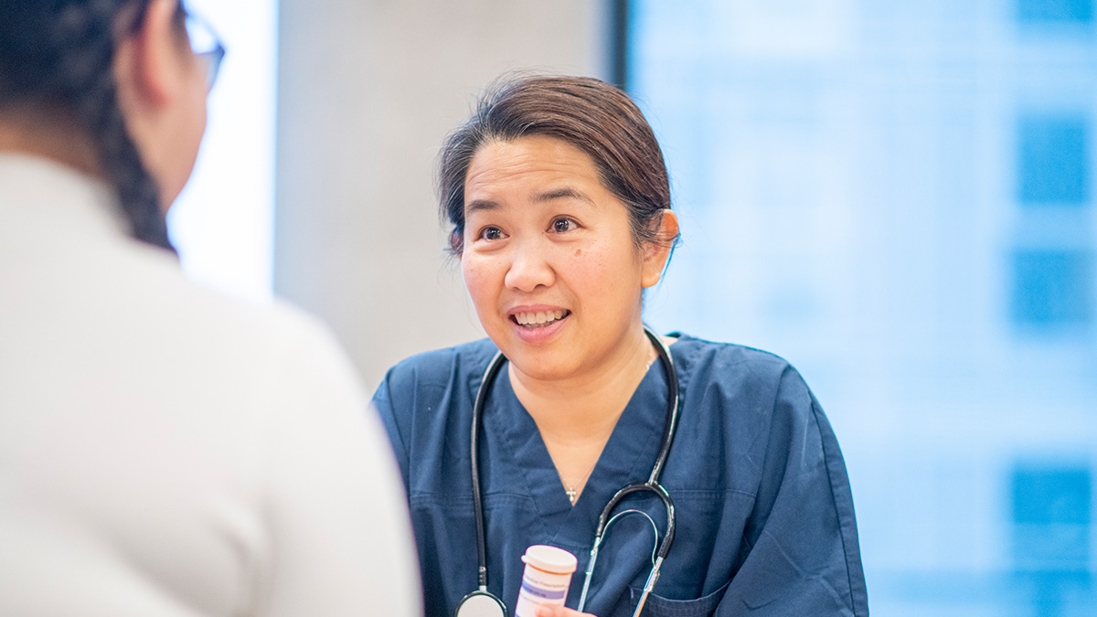 A healthcare professional holding a prescription bottle while meeting with a patient