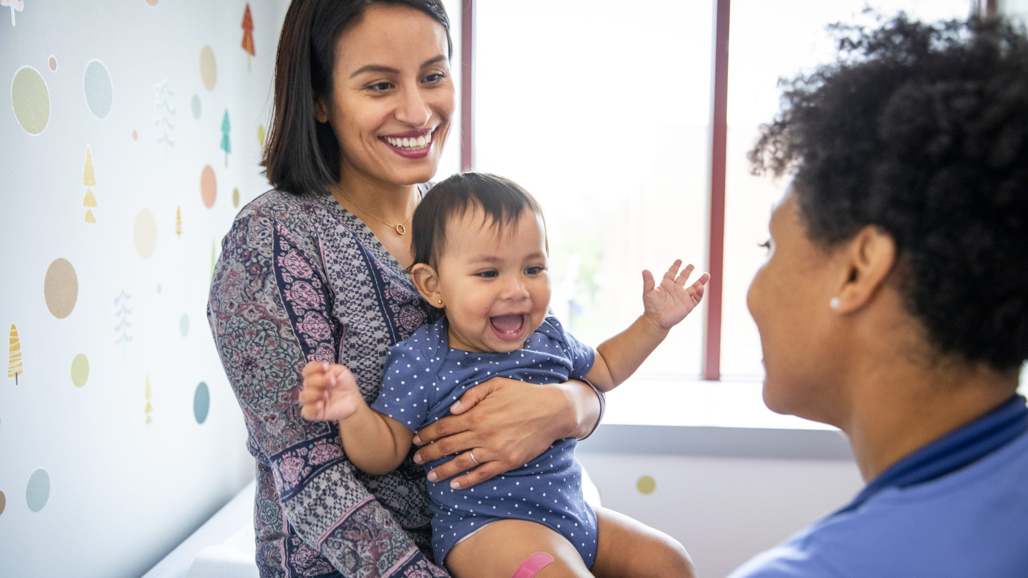 Mom holding baby following vaccination at a doctor's office.