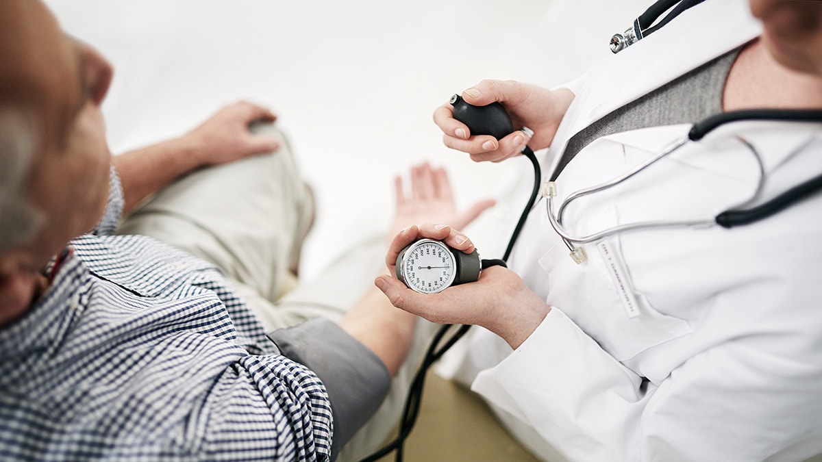 Health care professional measuring blood preasure of older man