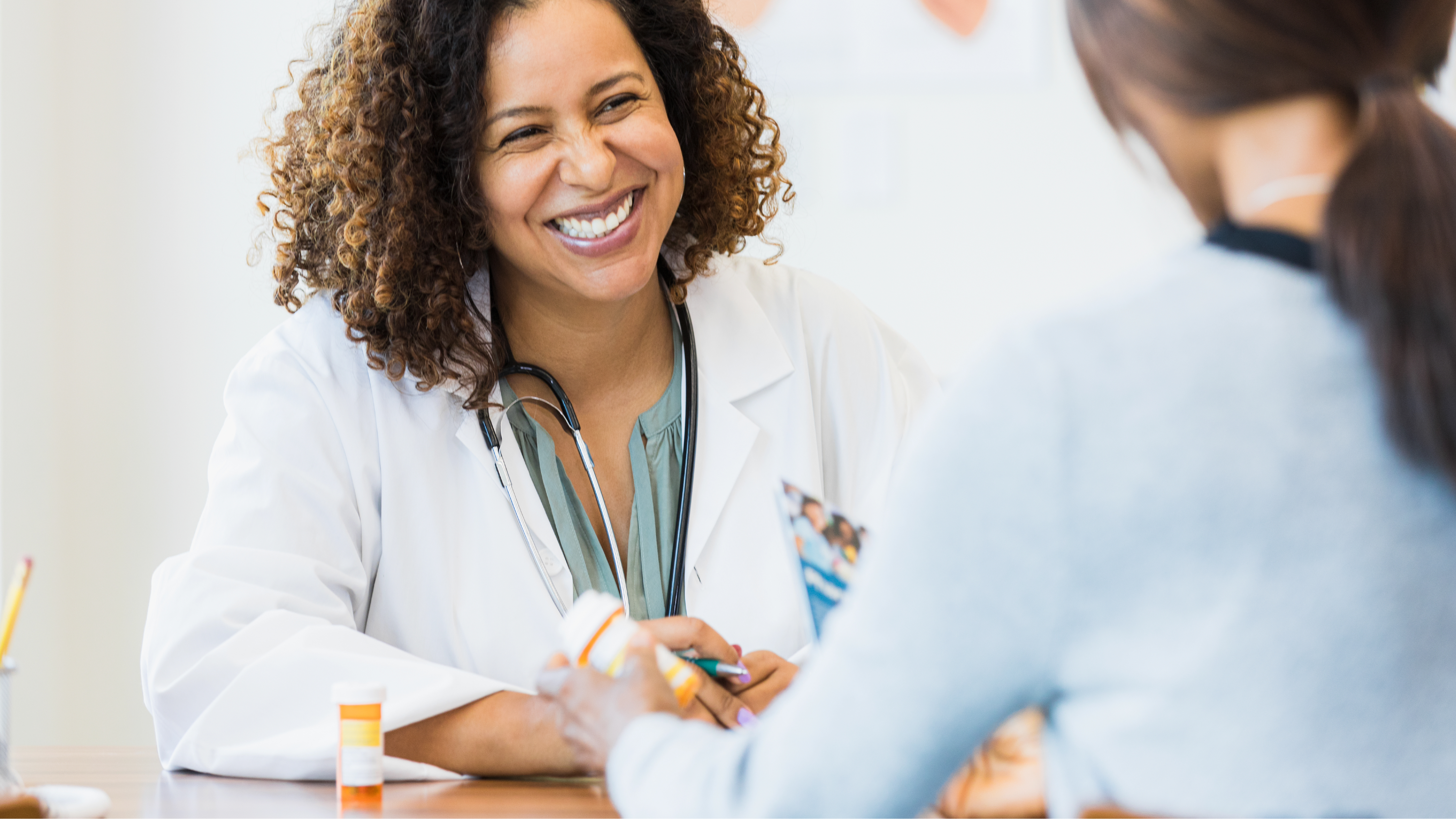 A smiling health care provider facing a patient.