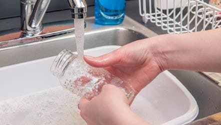 A person rinsing a bottle with safe water.