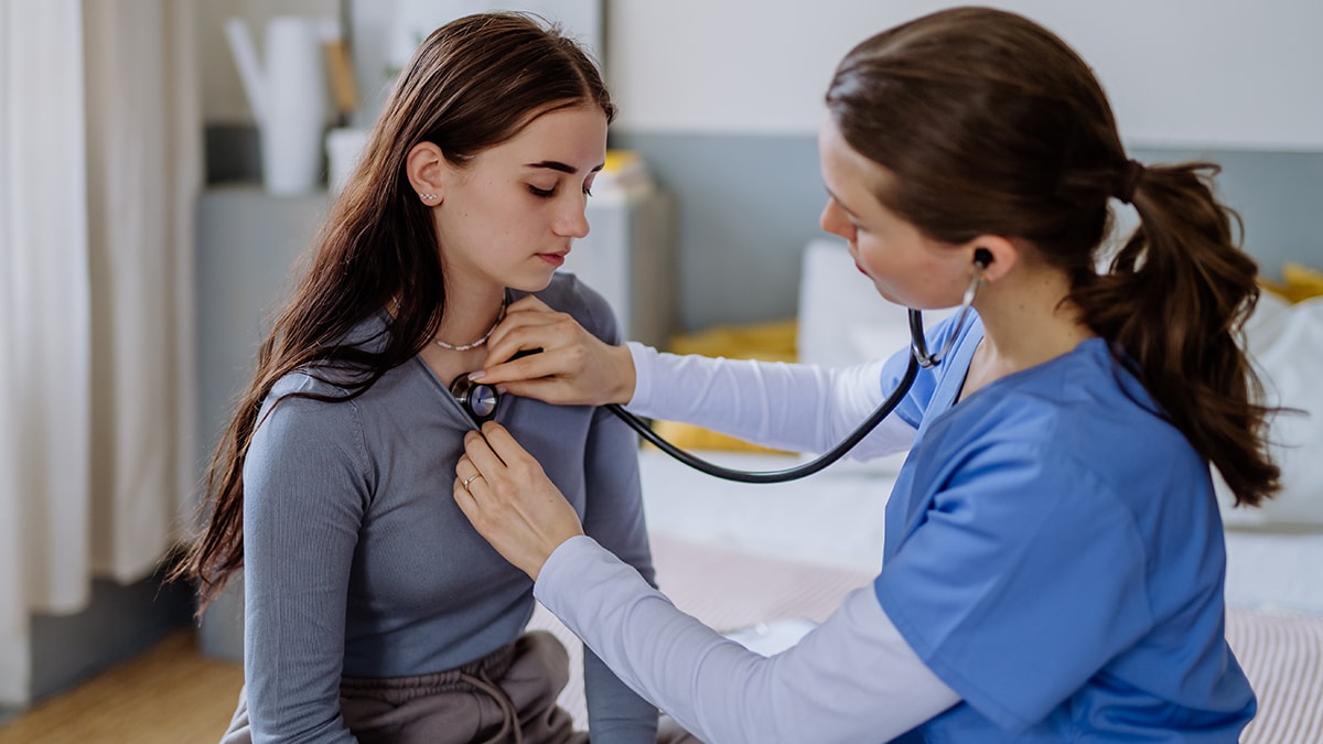 Young doctor examining teenage girl in her office.