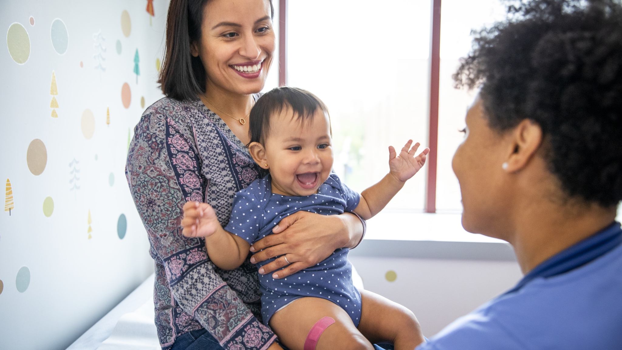 A smiling mother holds her infant child after vaccination.