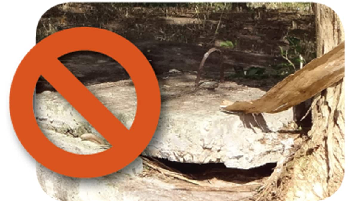 A broken cement septic tank cover with a "no" symbol.