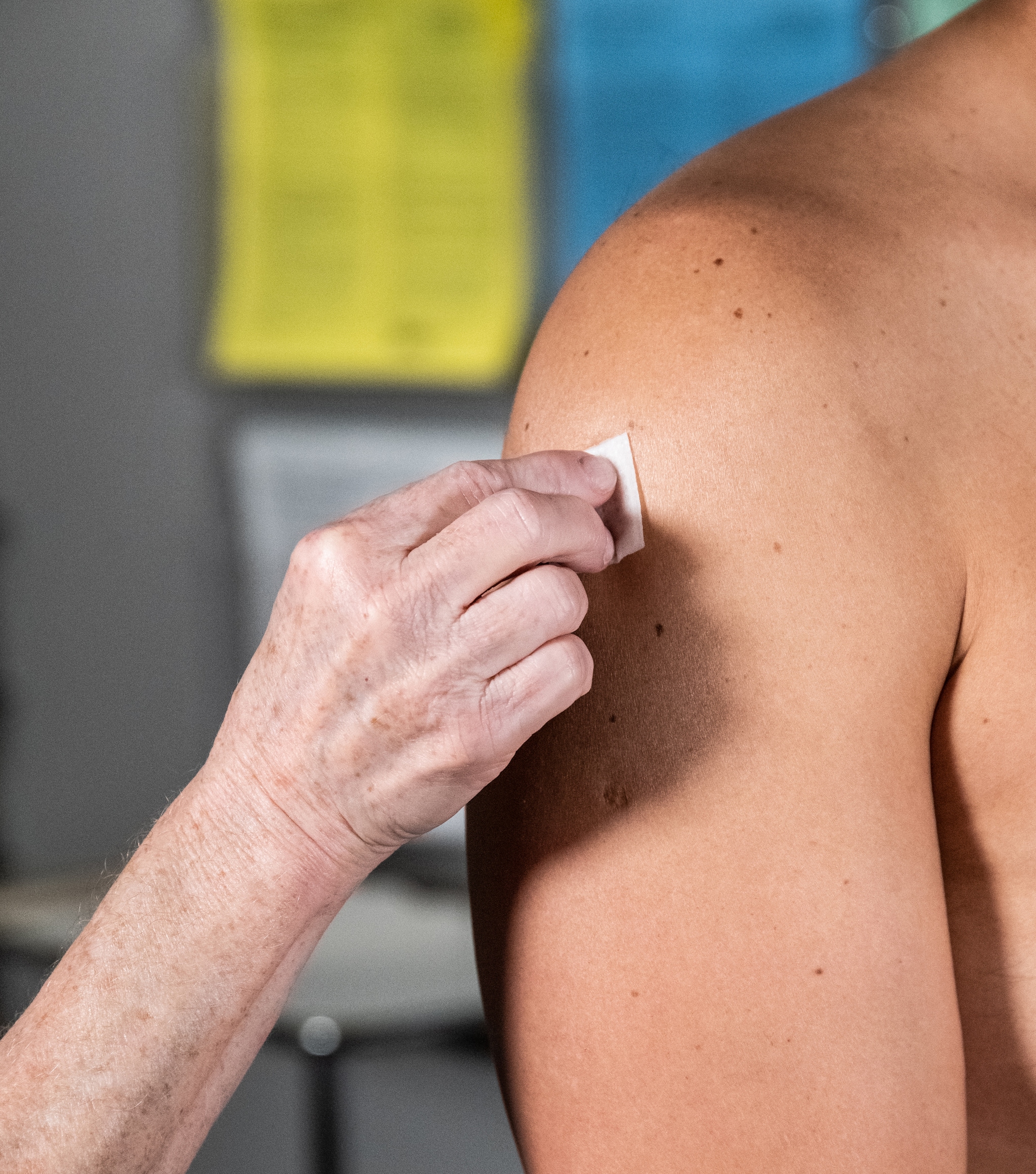 Image of a hand cleaning a light-skinned person's upper arm in preparation for vaccination.