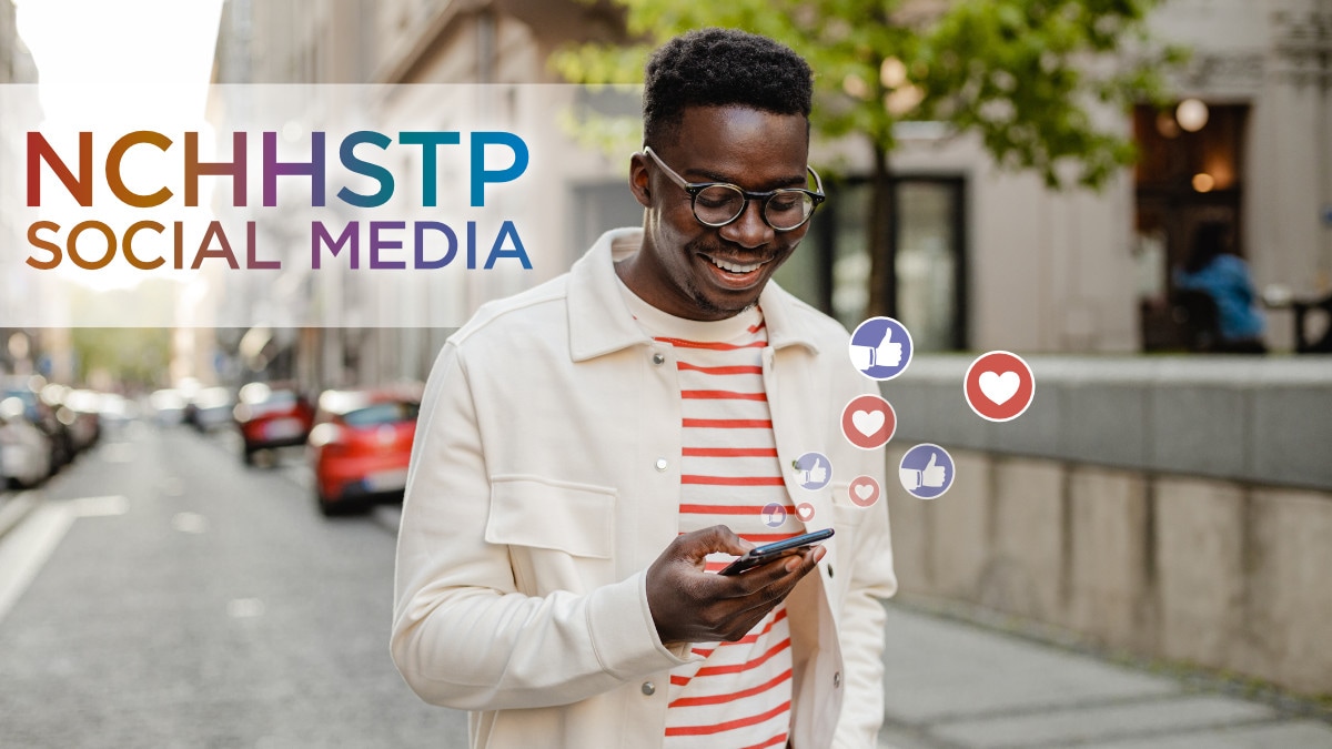 An African American man wearing glasses interacts with social media on his mobile phone.