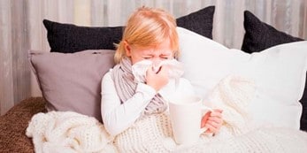 Child blowing nose in bed.