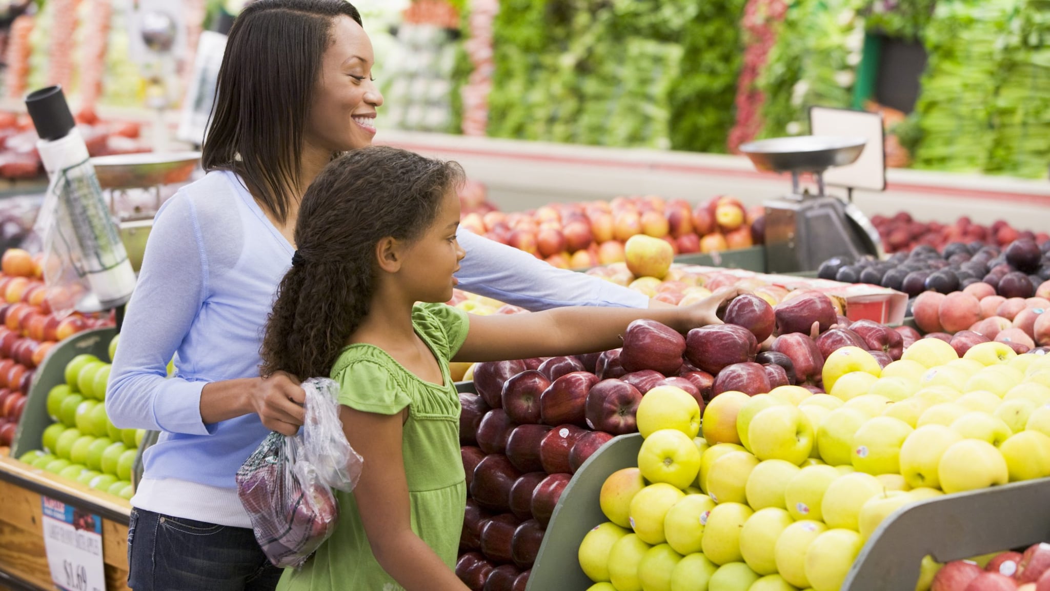 Mother and child selecting apples at grocery store