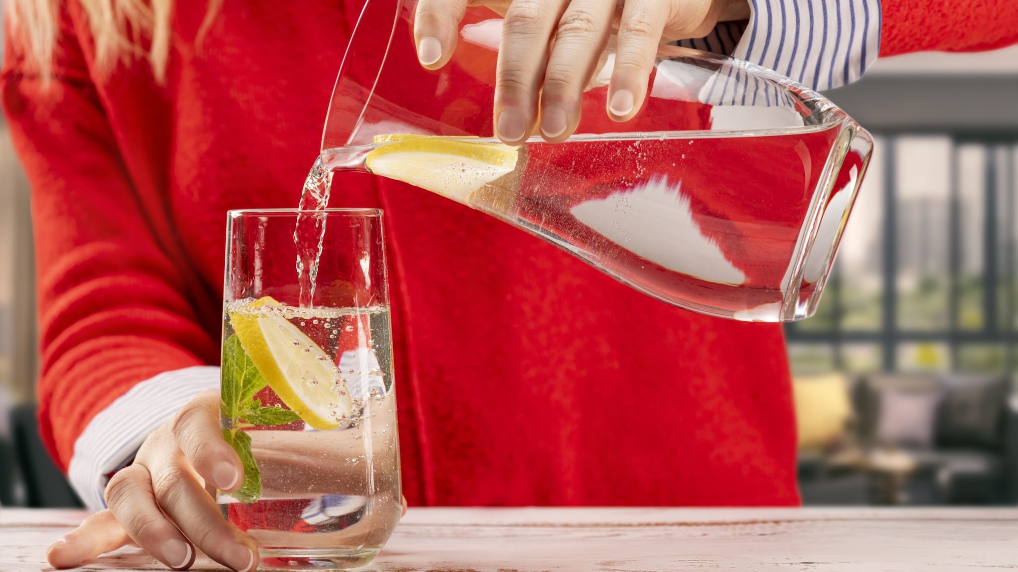 a picture of a pitcher of water with lemon slices being poured into a glass.