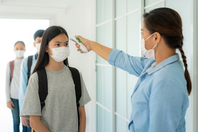 School administrator taking temperature of students