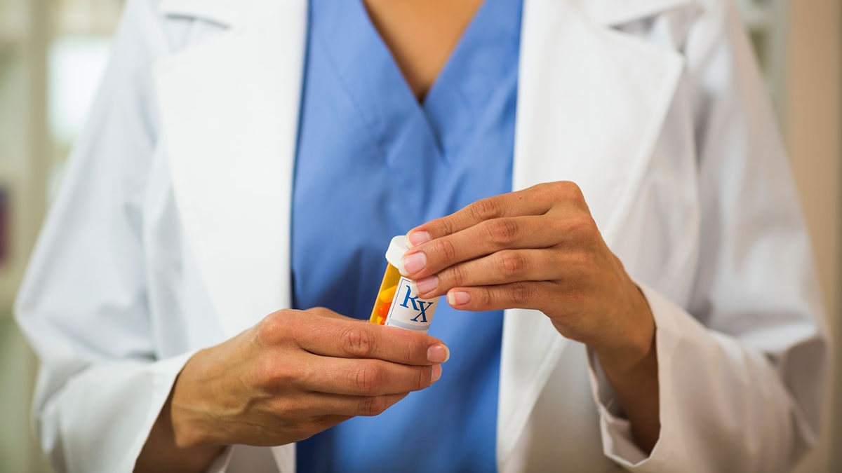 Closeup of a pharmacist holding a bottle of pills in her hand.