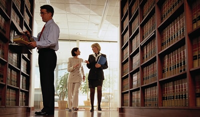 Three people standing in a research library.