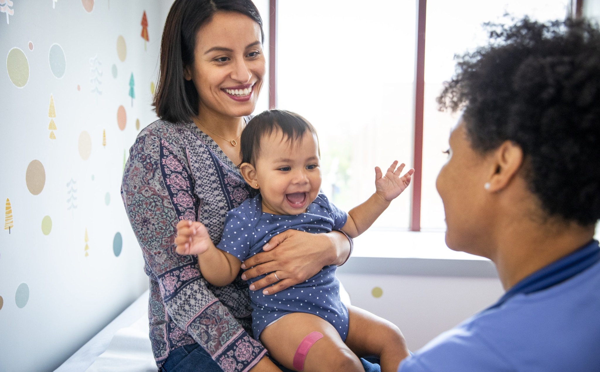 Smiling mother holding infant at the doctor's office.