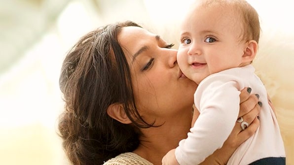 mother kissing smiling baby