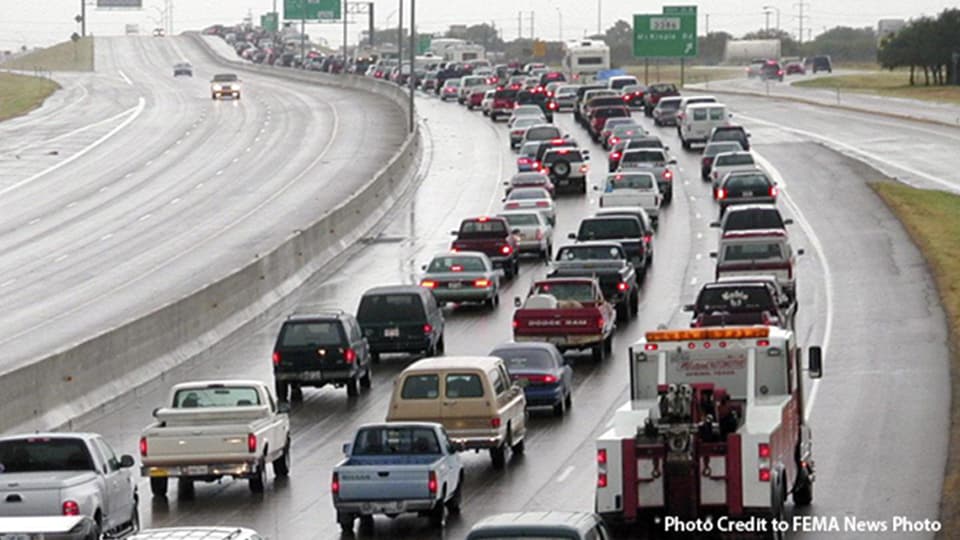 Dozens of cars and trucks in a traffic jam on a three lane highway.