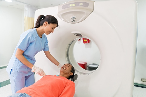 A healthcare professional preparing a patient to enter an x-ray machine.